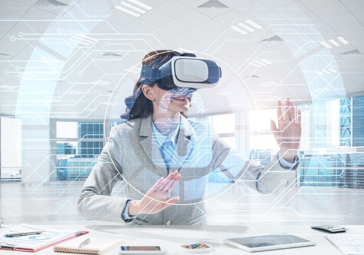 Horizontal shot of confident young business woman in suit using virtual reality headset and safety interface while sitting inside office building.
